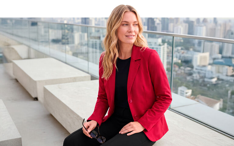 Dame in rotem Blazer vor einer Skyline